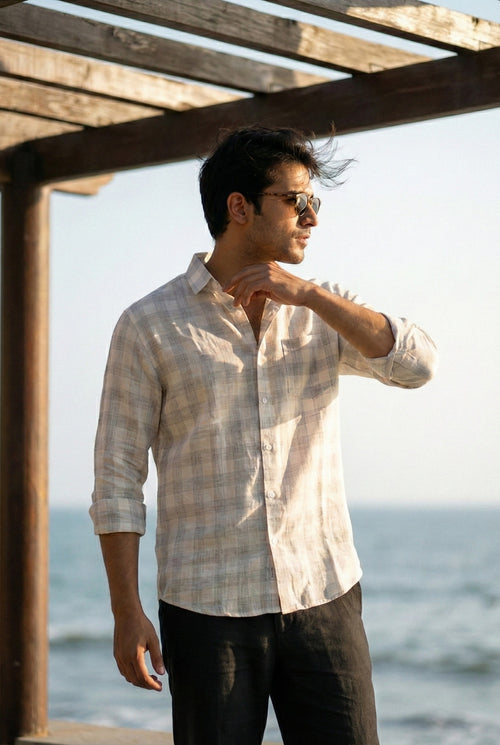 Men’s lightweight linen check shirt worn in a coastal setting, featuring breathable fabric and relaxed fit for summer work-casual and resort wear.