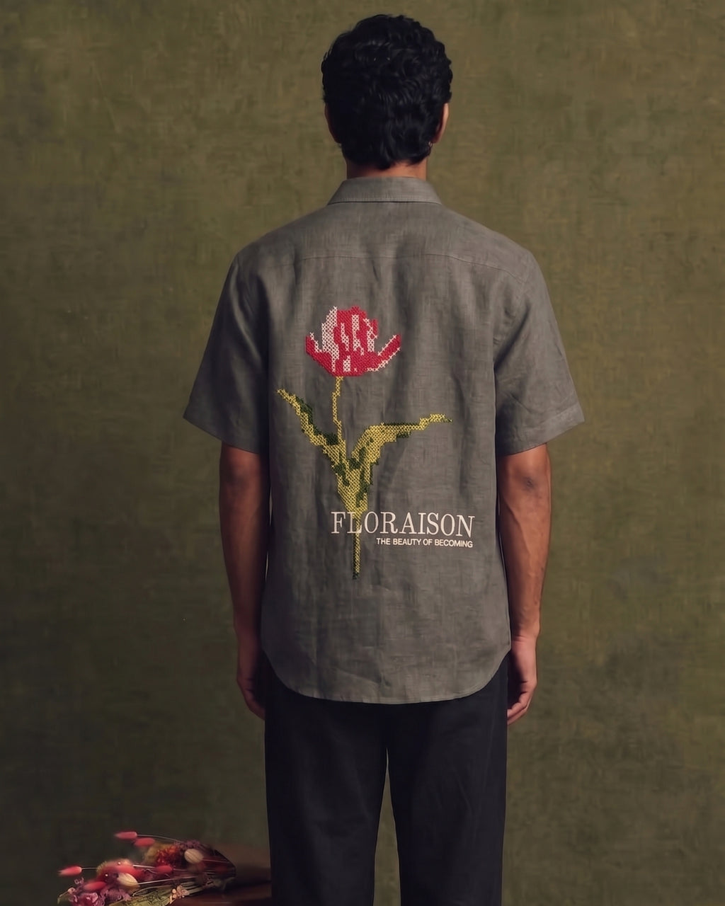 Grey linen short-sleeve shirt with a classic collar, button-front closure, and large floral embroidery with “FLORAISON” lettering across the back.