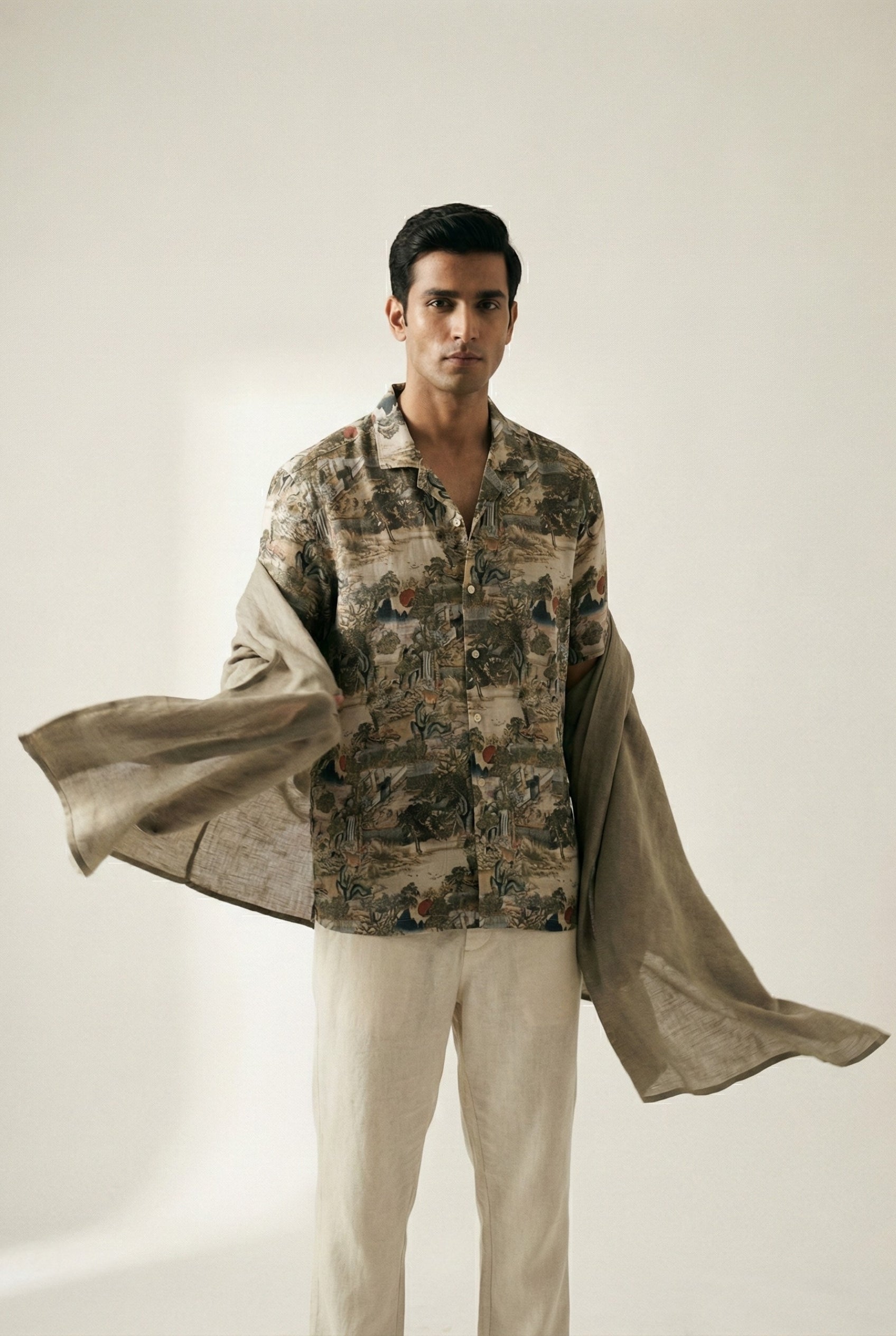 Man wearing an illustrated print shirt with a softly tailored silhouette, captured in motion as lightweight fabric moves naturally, emphasizing artisanal design and elevated contemporary menswear.