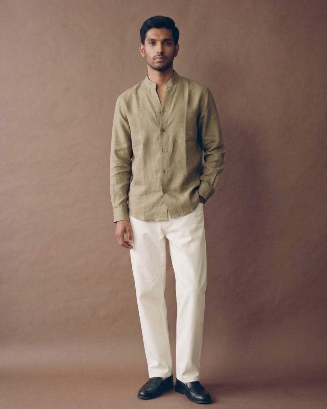 Golden beige linen shirt with a band collar, full button-front closure, long sleeves, and a relaxed fit, paired with white trousers.