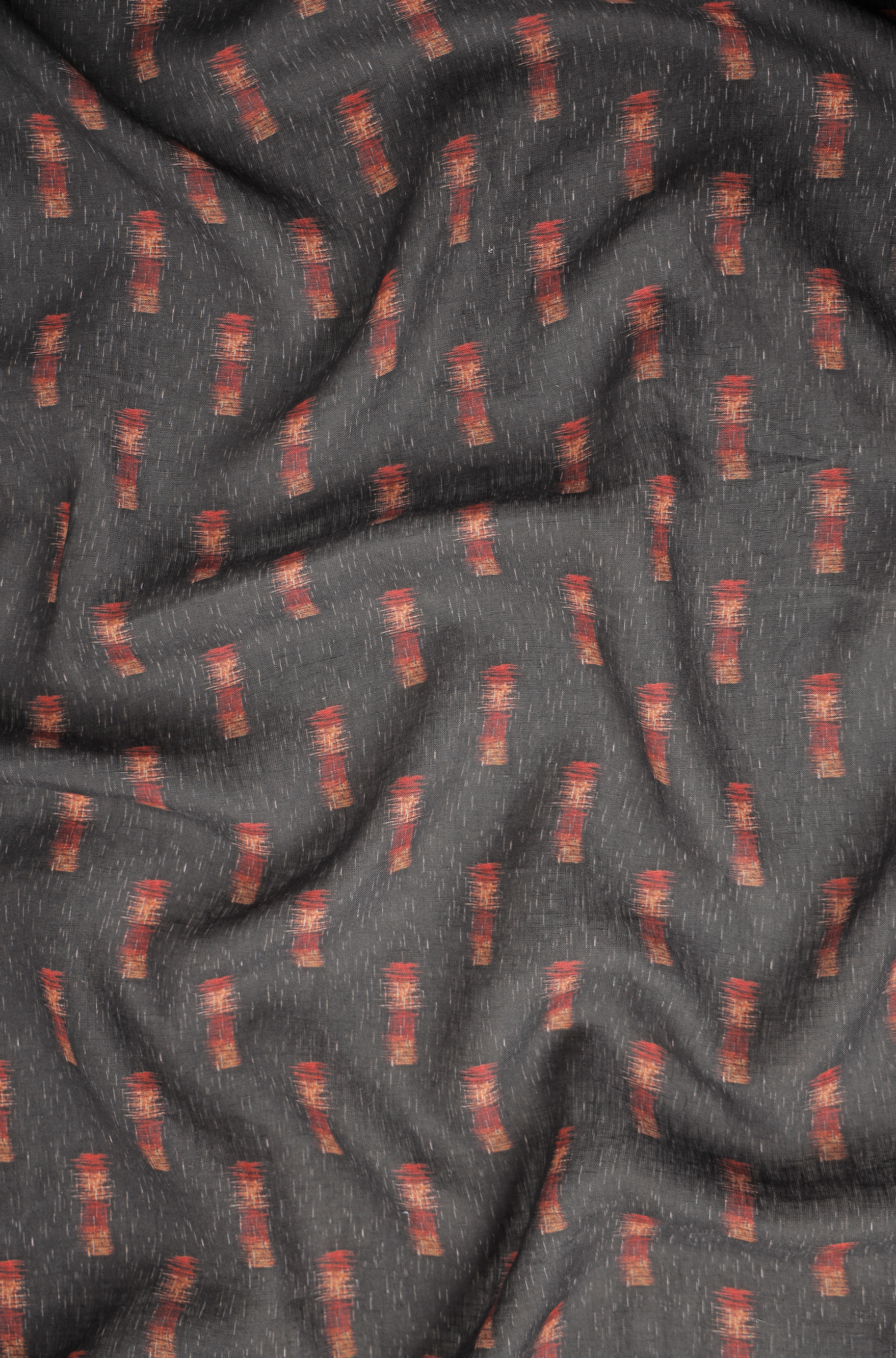 Dark charcoal grey linen fabric with subtle ikat-inspired rust and terracotta motifs, showcasing a soft texture and natural drape for premium men’s shirts