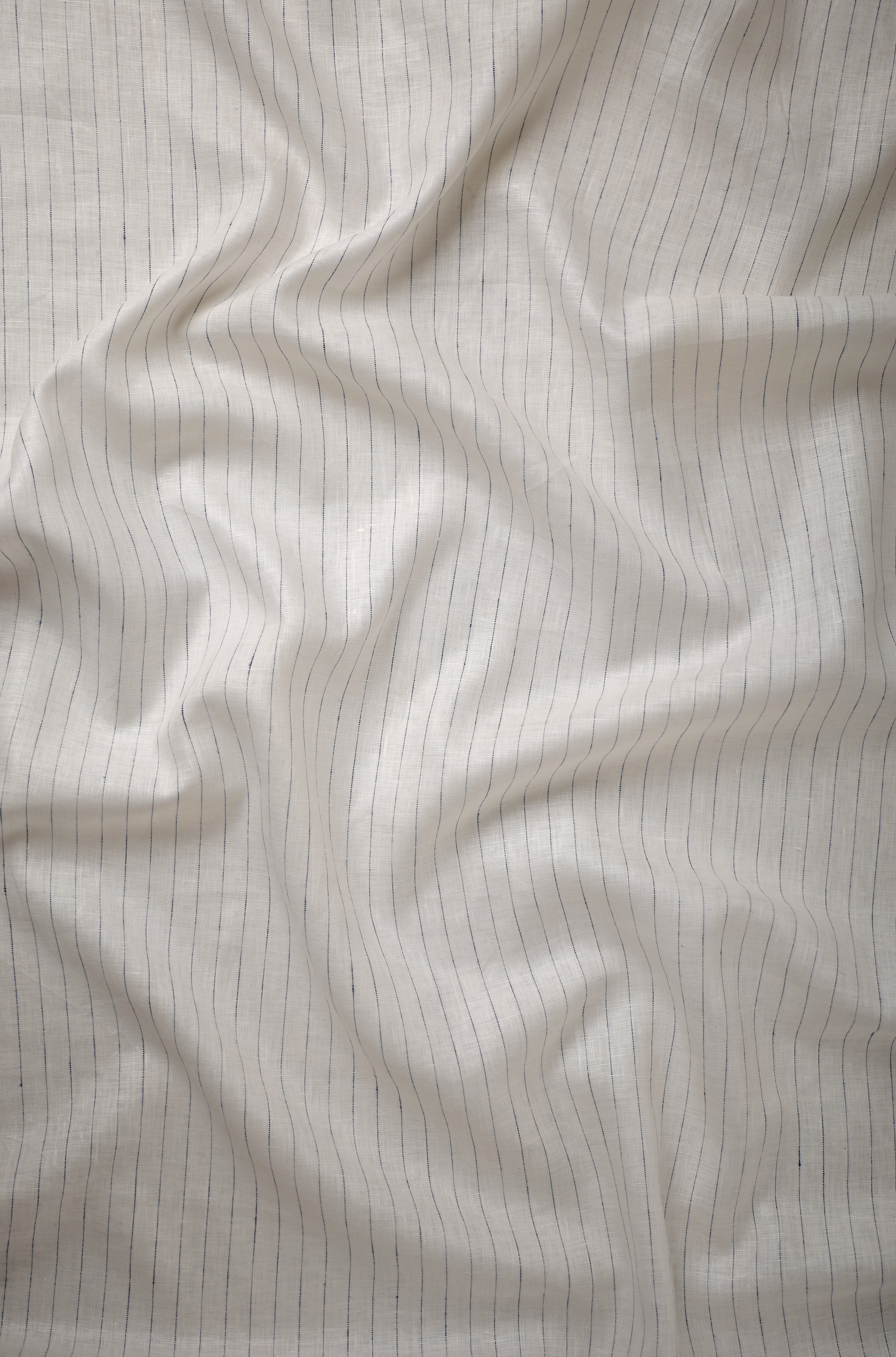 Lightweight off-white linen fabric with fine linear pinstripes, highlighting fluid drape, refined weave, and a clean contemporary surface.