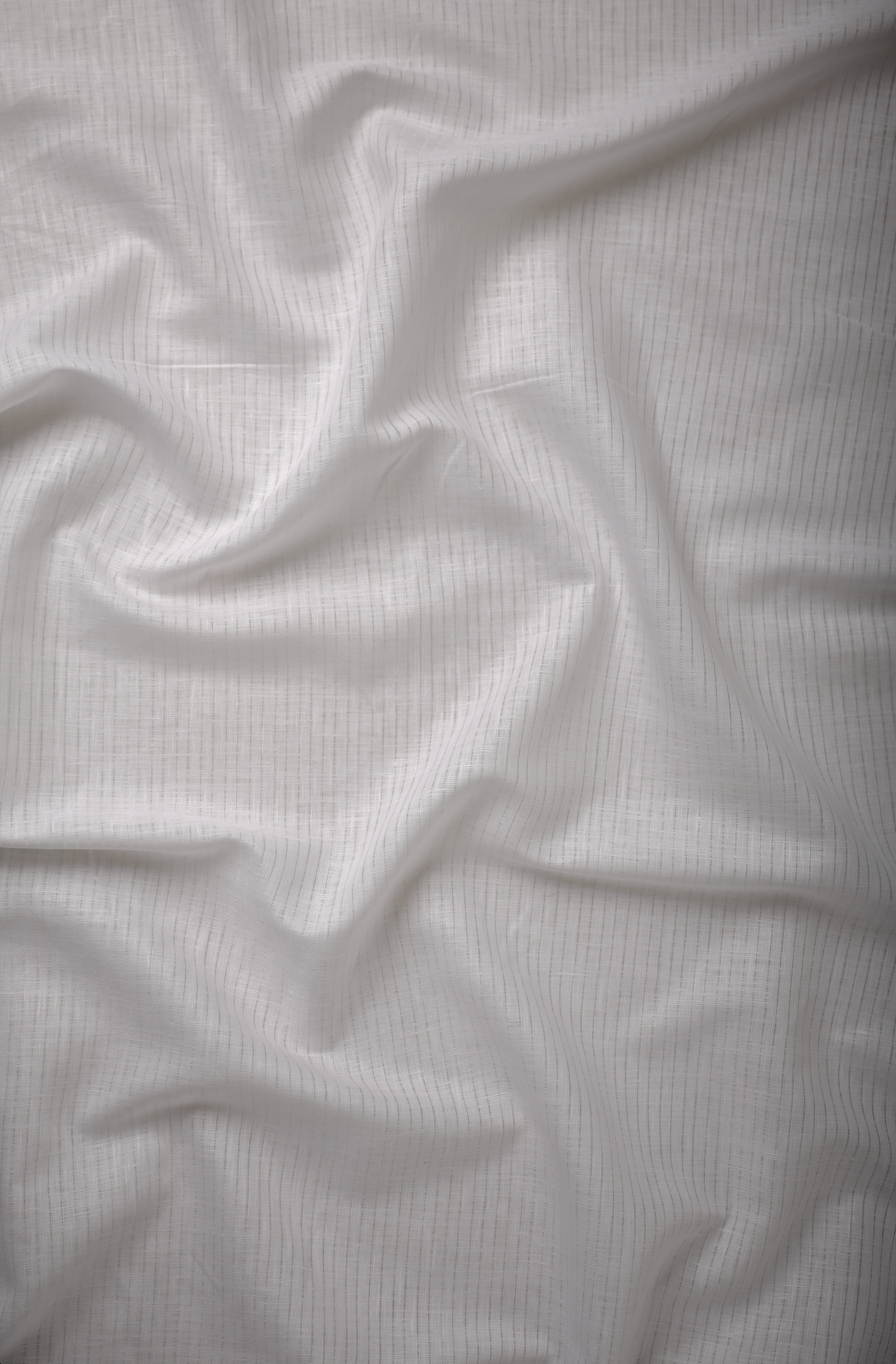 Soft white linen fabric with a fine cross weave, captured to show natural translucency, breathable texture, and gentle fabric movement.