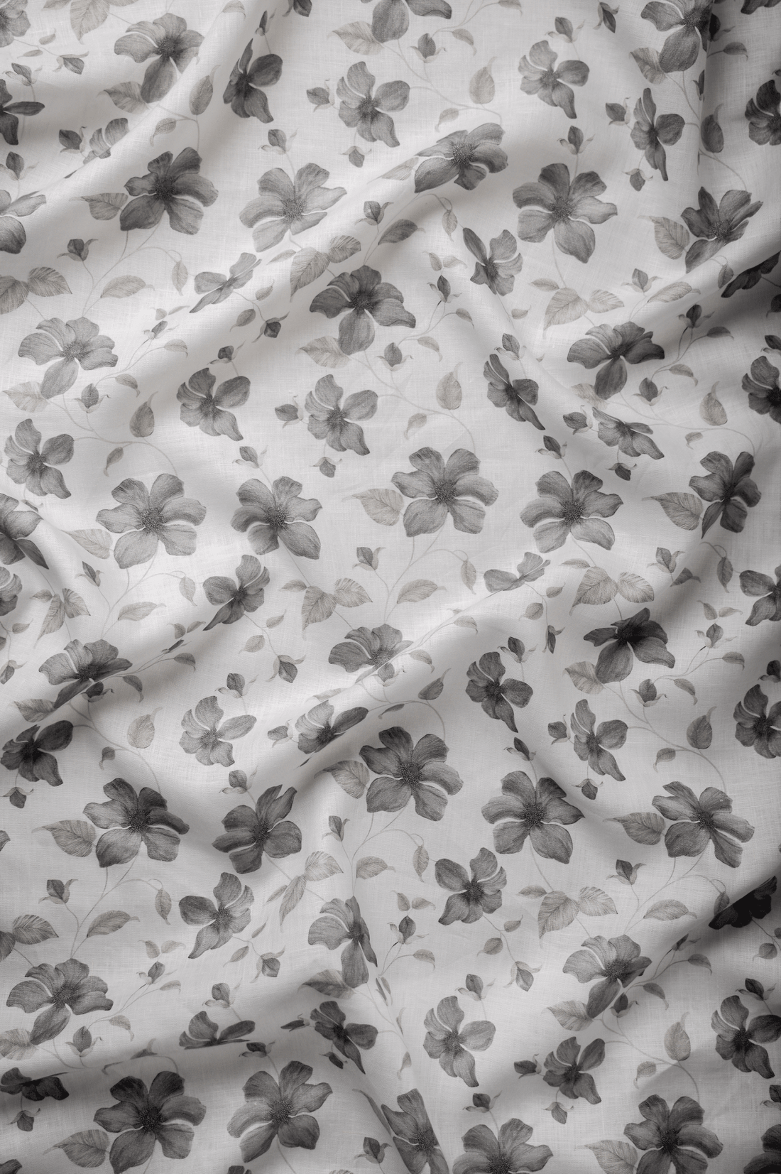 Flat lay of Gulzar 60 lea pure linen fabric, a charcoal floral print on white. Sold by the metre by Tyra