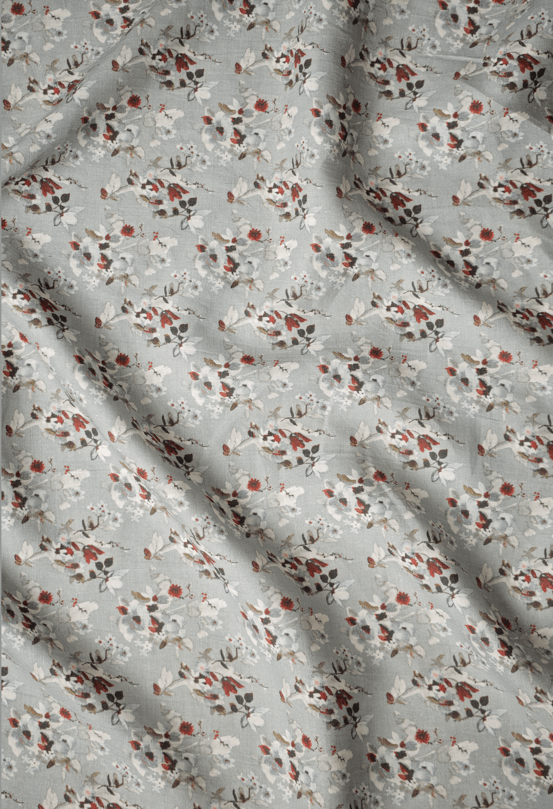 Flat lay of Nandan 60 lea pure linen fabric, a rust and cream floral print on pale grey-green. Sold by the metre by Tyra