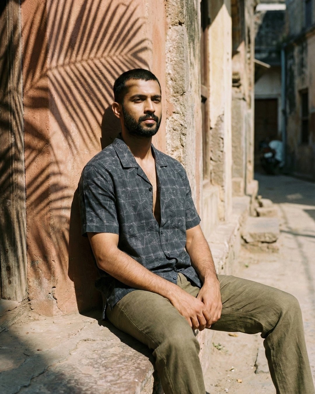 Man seated in a lane in an Indian city, wearing the Neelvara pure linen shirt by Tyra