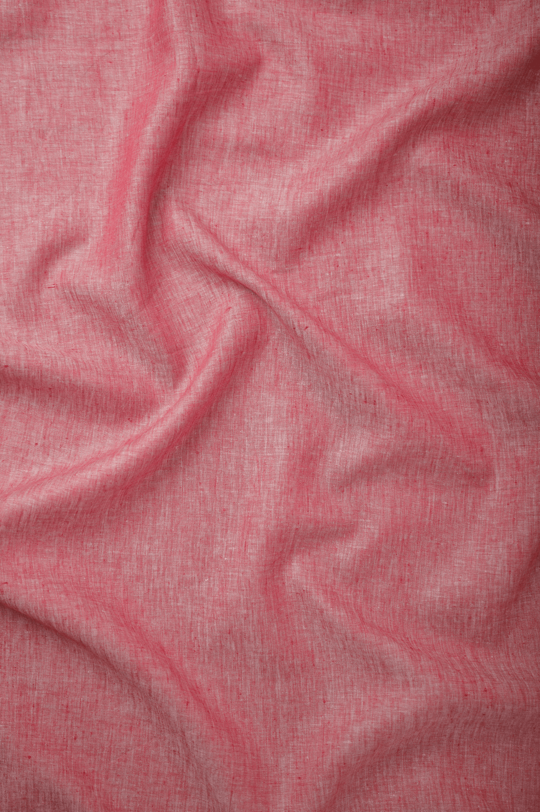 Flat lay of Raktā 60 lea pure linen fabric in coral rose, showing the weave. Sold by the metre by Tyra