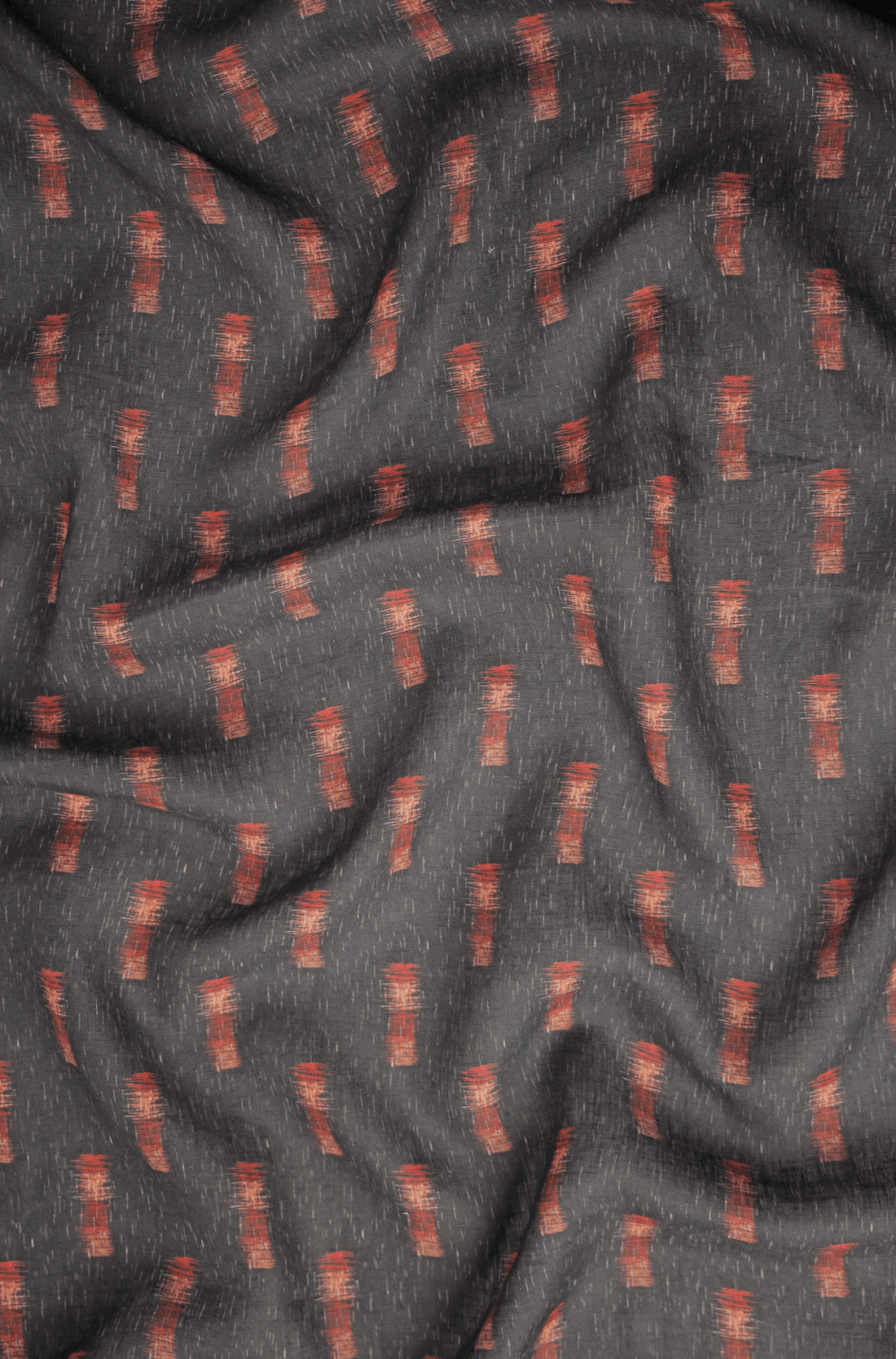 Flat lay of Rānga 60 lea pure linen fabric, a rust brushstroke print on charcoal. Sold by the metre by Tyra