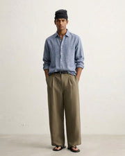 Man in the Unwritten Blue long-sleeve pure linen shirt by Tyra with olive wide-leg trousers and a black head wrap