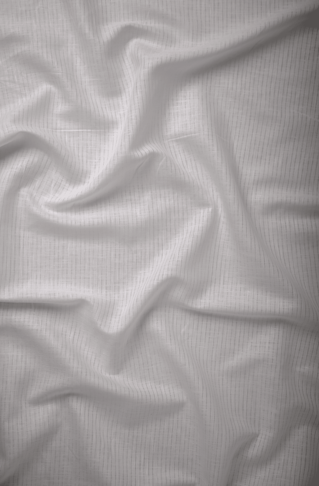Flat lay of Vāyu White 60 lea pure linen fabric in white with fine self stripes. Sold by the metre by Tyra