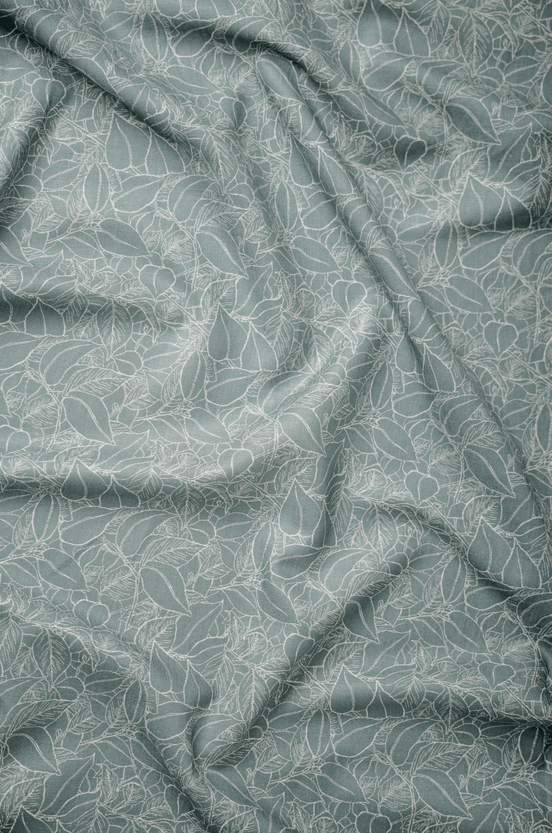 Flat lay of Vriksha 60 lea pure linen fabric, a white line-drawn leaf print on sage green. Sold by the metre by Tyra